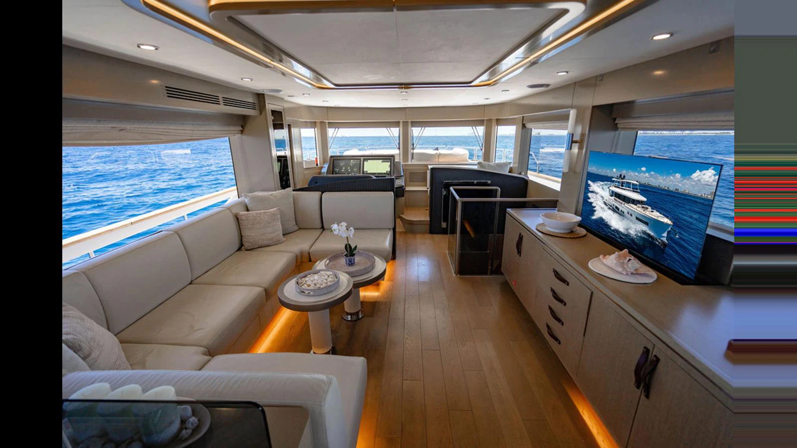 The salon offers a spacious and luxurious seating area with a large TV and panoramic windows for stunning ocean views. aboard NIVASA Yacht for Sale