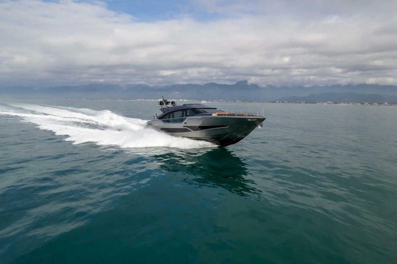 A sleek yacht cruises swiftly across calm waters under a cloudy sky. aboard AB 100/05 Yacht for Sale