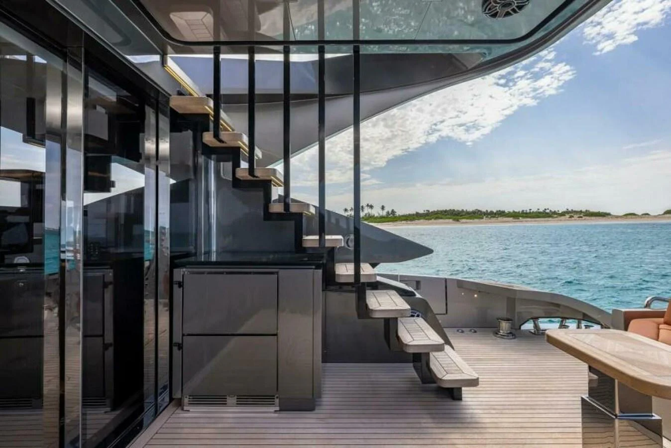 The aft deck features sleek modern design with a staircase leading to the upper deck and a view of the serene ocean. aboard AB 100/05 Yacht for Sale