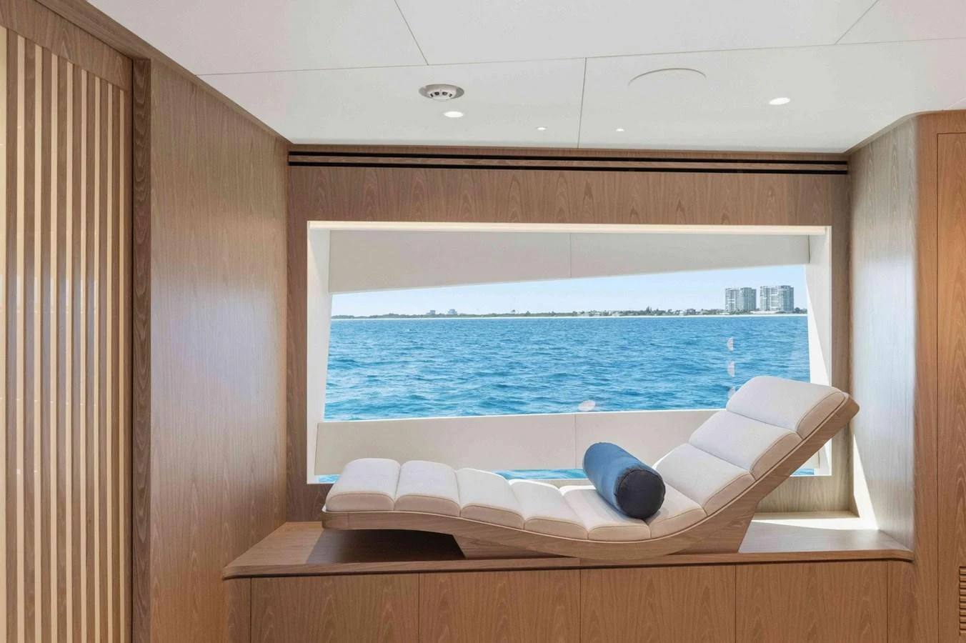 A serene lounge area with a comfortable chaise longue and a large window offering a stunning ocean view. aboard THE ROCK Yacht for Sale