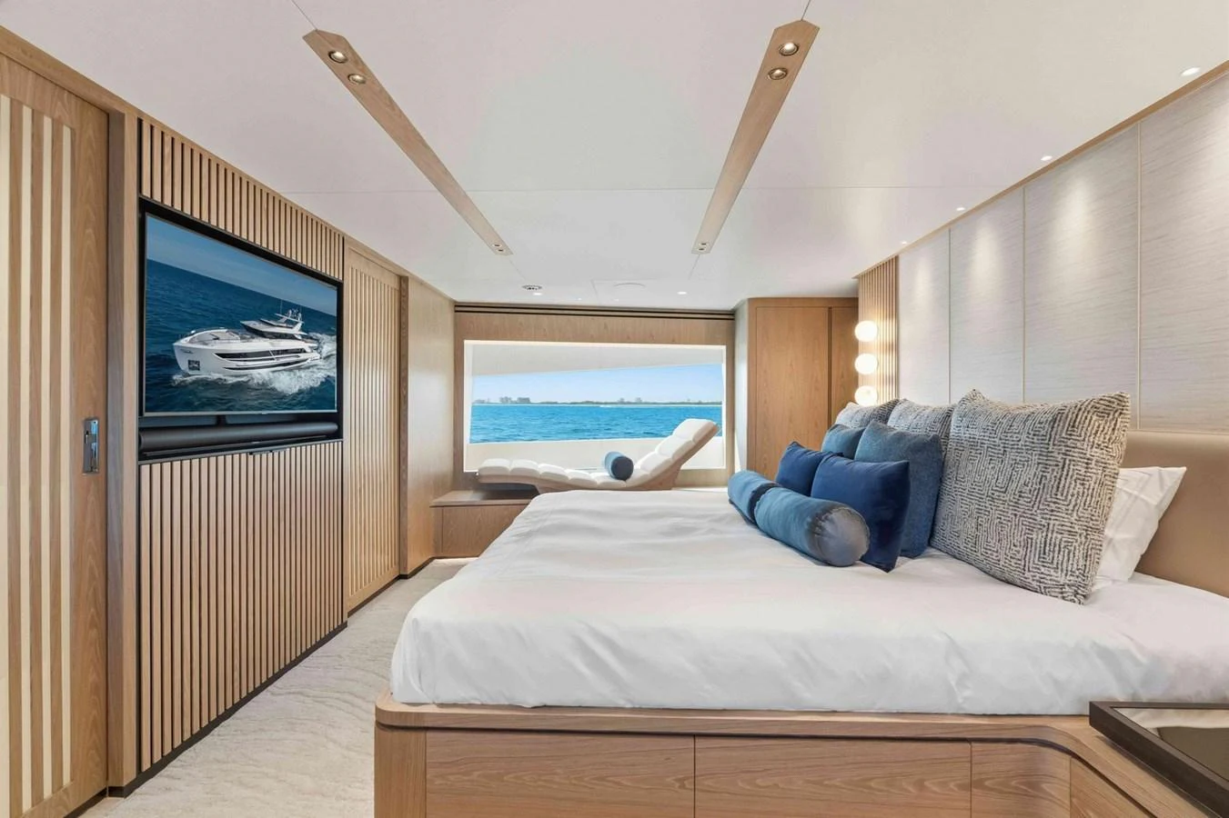 The stateroom features a luxurious bed with a scenic ocean view through a large window. aboard THE ROCK Yacht for Sale