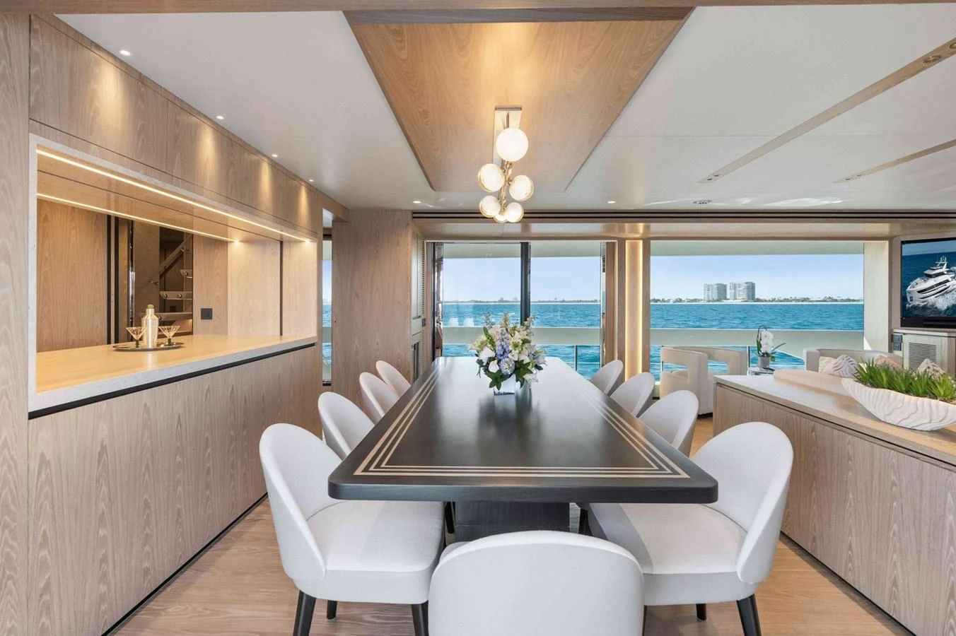 The yacht's dining area features a sleek table with comfortable seating and panoramic ocean views. aboard THE ROCK Yacht for Sale
