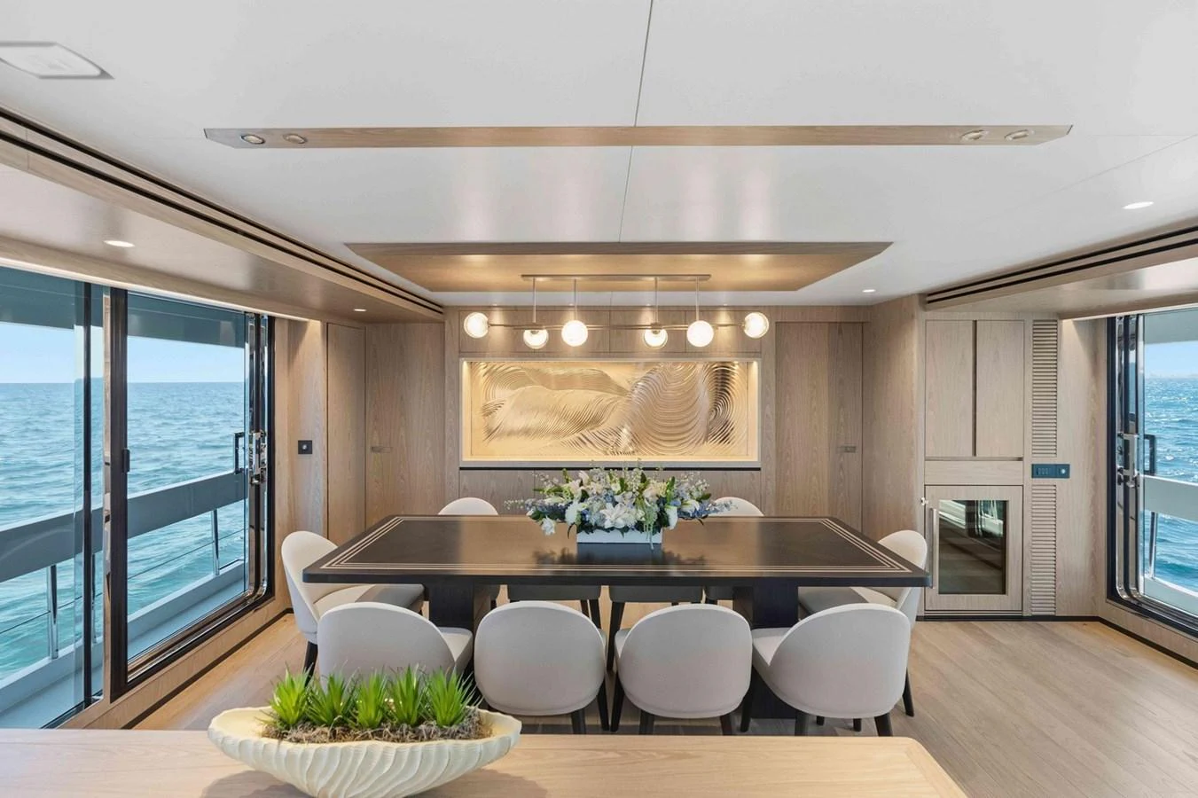 The yacht's dining area features a modern table with elegant seating and panoramic ocean views. aboard THE ROCK Yacht for Sale