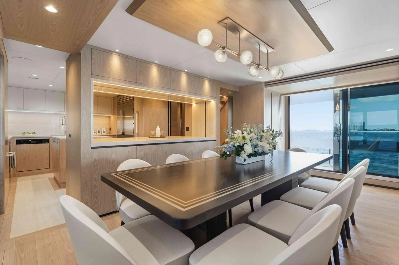 The yacht's dining area features a sophisticated table setting with a view of the sea through large windows. aboard THE ROCK Yacht for Sale