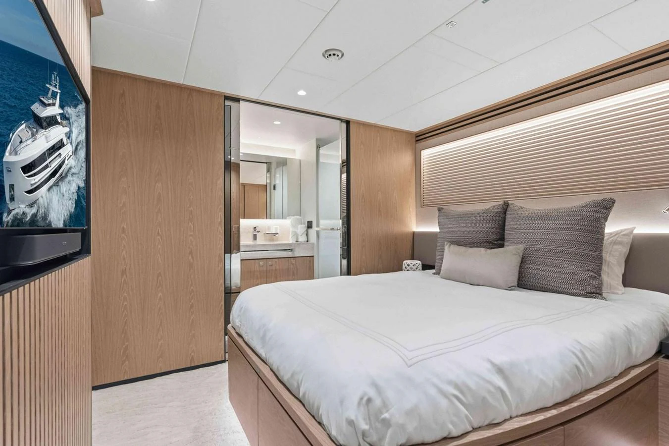 The stateroom features a comfortable bed with modern decor and a view into the ensuite bathroom. aboard THE ROCK Yacht for Sale