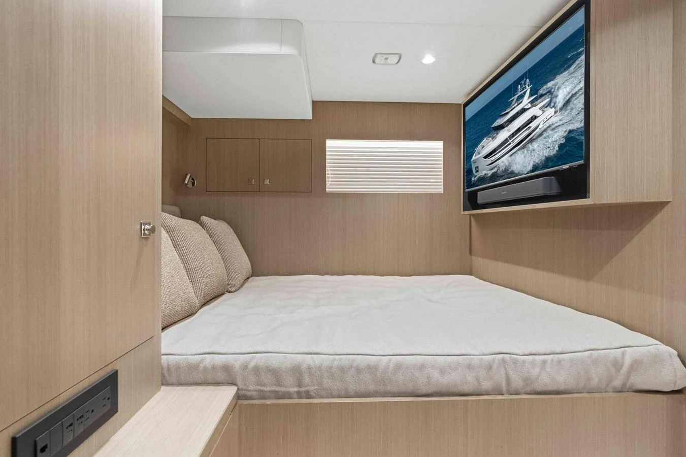 A cozy stateroom with a large bed and a flat-screen TV displaying a yacht image. aboard THE ROCK Yacht for Sale