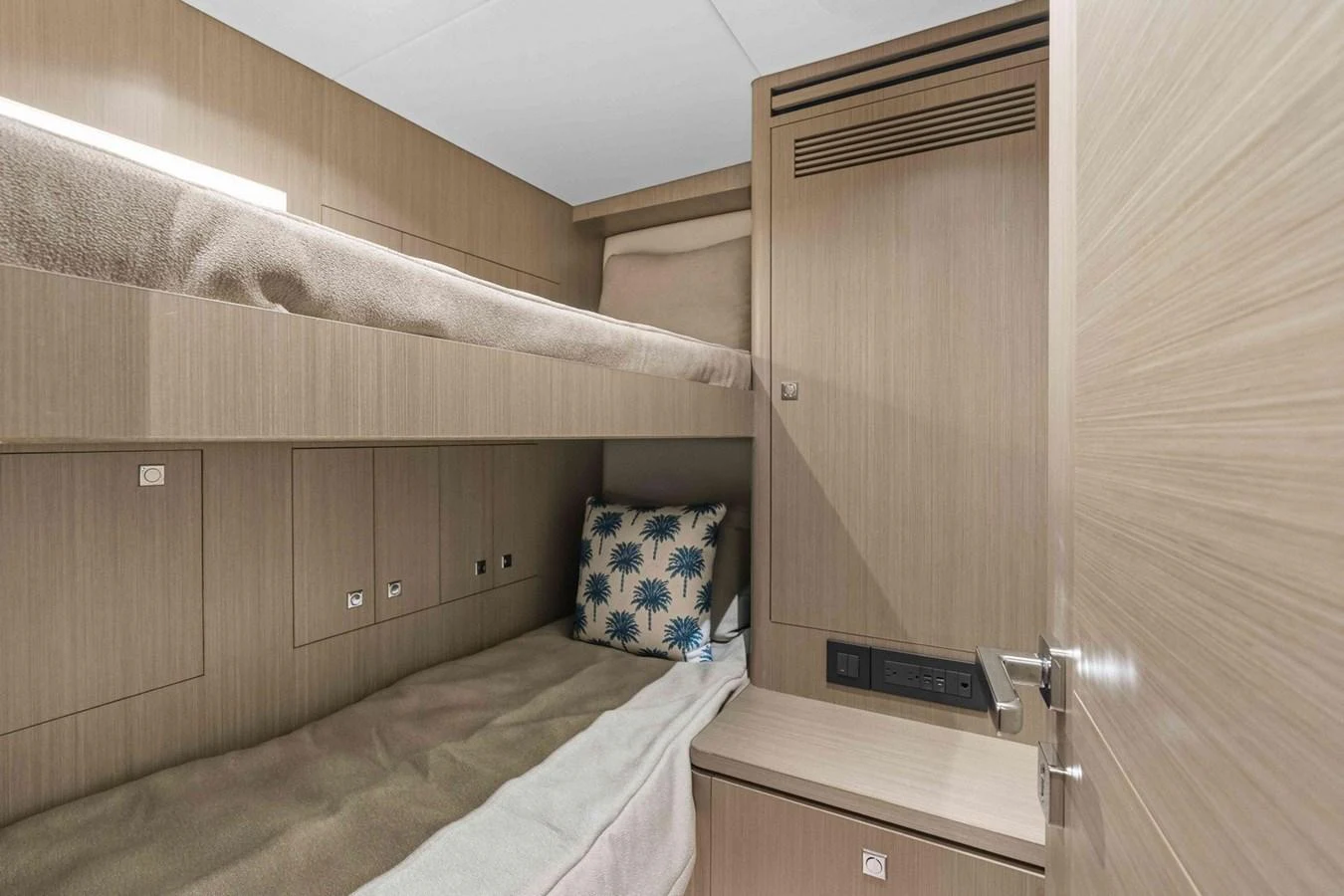 The cozy bunk cabin features modern wood paneling and comfortable bedding. aboard THE ROCK Yacht for Sale