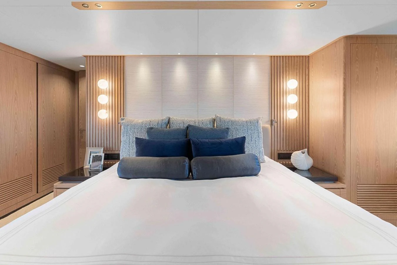 The master stateroom features a luxurious bed with plush pillows and elegant wooden accents. aboard THE ROCK Yacht for Sale