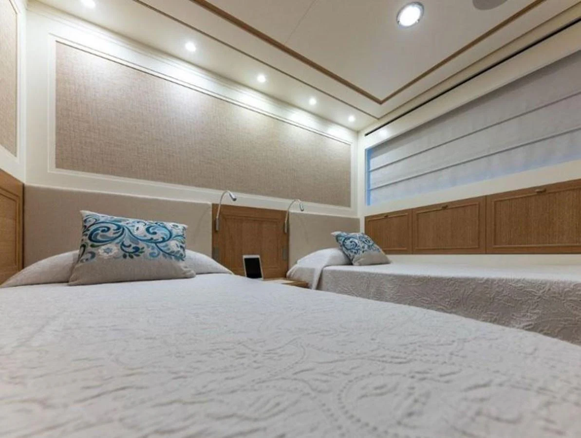 The guest stateroom features twin beds with elegant bedding and soft lighting. aboard O Yacht for Sale