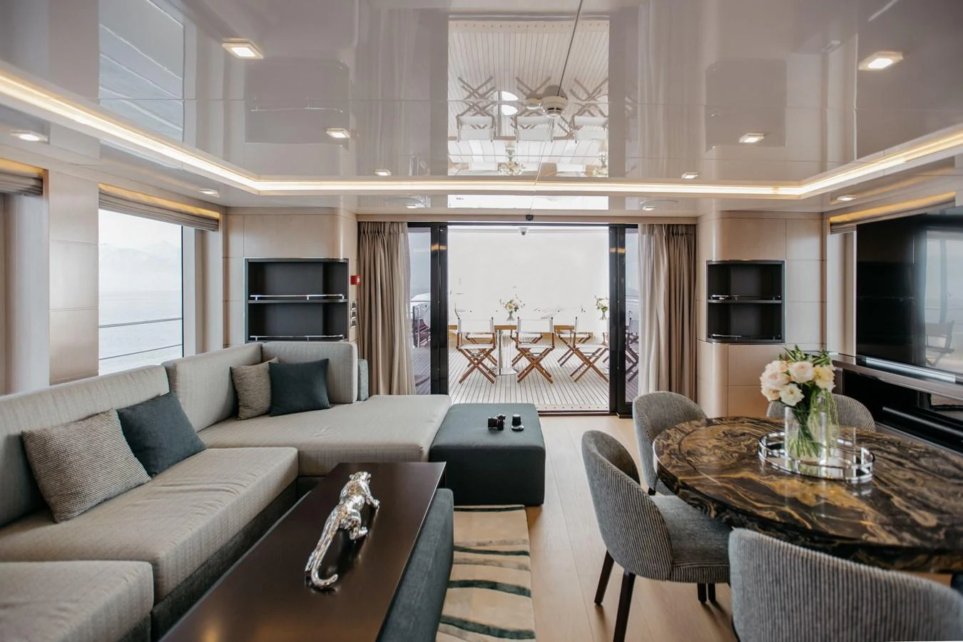 The salon features elegant furnishings with a comfortable seating area and a stylish dining table. aboard BERING 145 Yacht for Sale