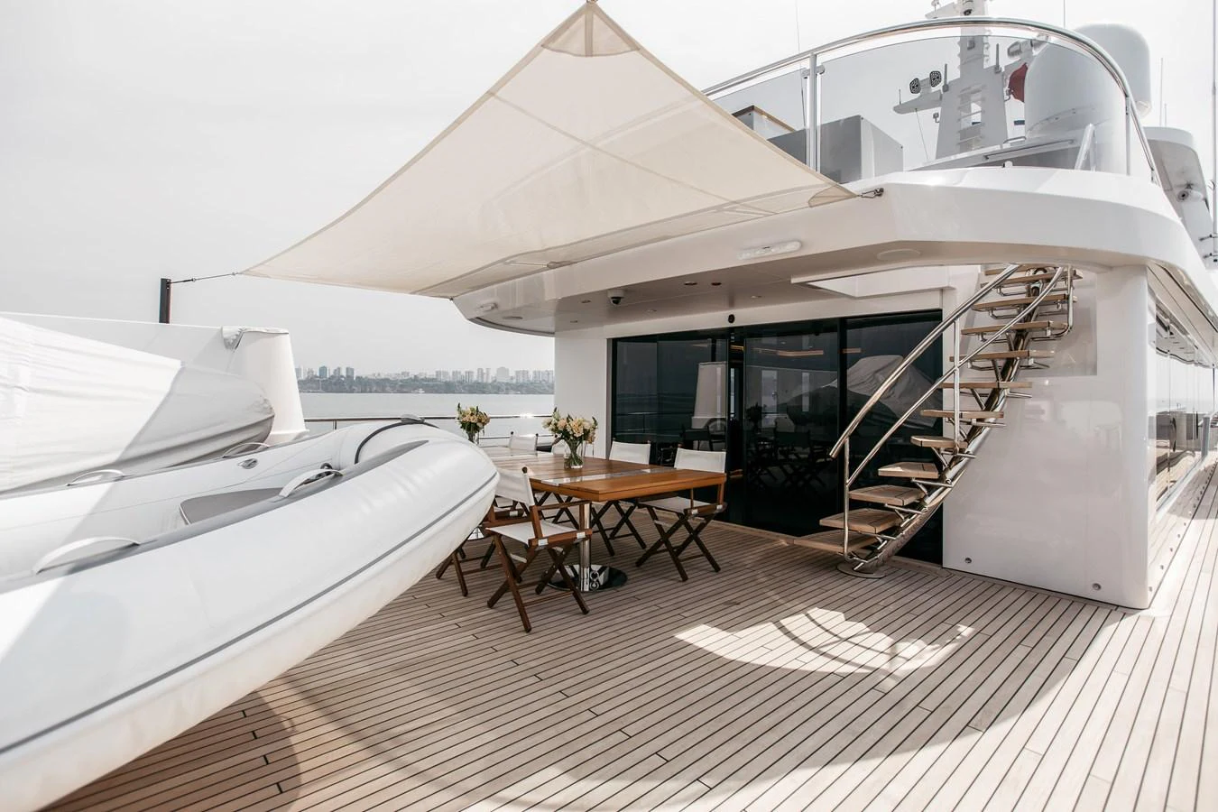 The aft deck features a stylish dining area with a modern staircase leading to the upper deck. aboard BERING 145 Yacht for Sale