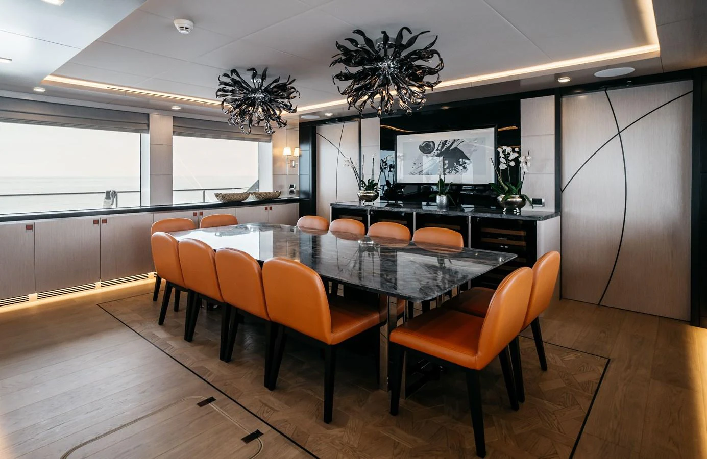 The yacht's dining area features a sleek table with comfortable seating and modern lighting fixtures. aboard BERING 145 Yacht for Sale