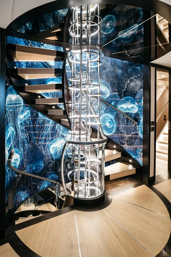 A stunning spiral staircase with a unique jellyfish-themed wall design. aboard BERING 145 Yacht for Sale
