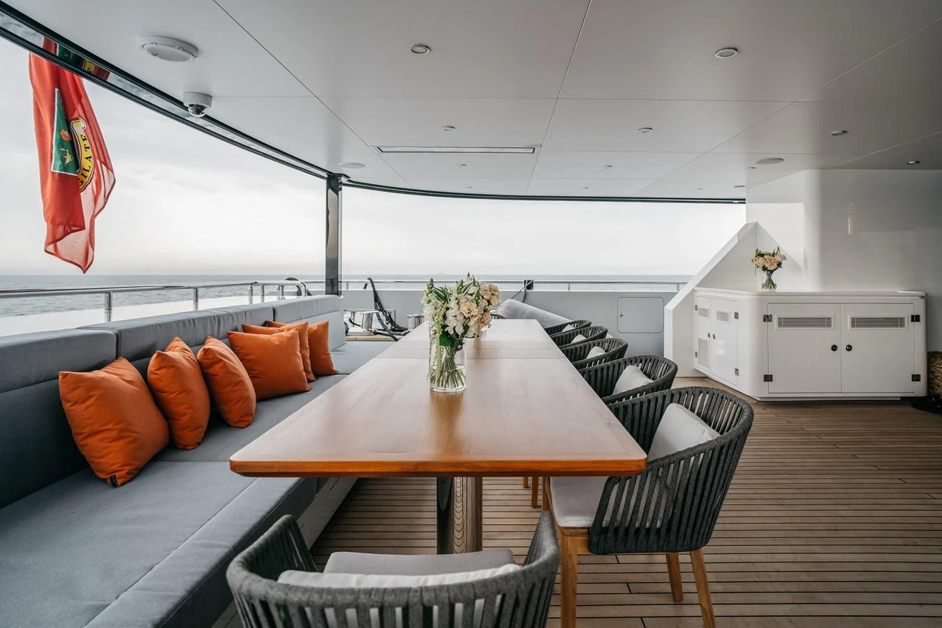 The aft deck features a spacious dining area with a sleek wooden table and comfortable seating, perfect for alfresco dining. aboard BERING 145 Yacht for Sale