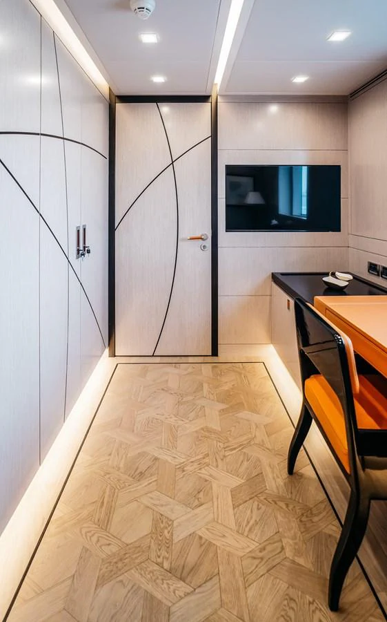 A modern yacht interior featuring a sleek workspace with a wall-mounted TV and stylish wood flooring. aboard BERING 145 Yacht for Sale