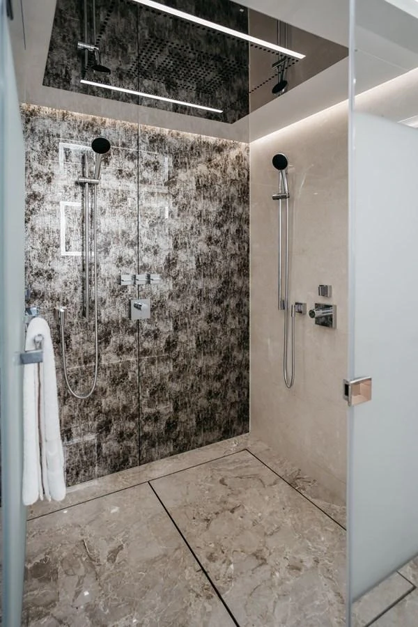 A luxurious shower area with modern fixtures and elegant marble flooring. aboard BERING 145 Yacht for Sale