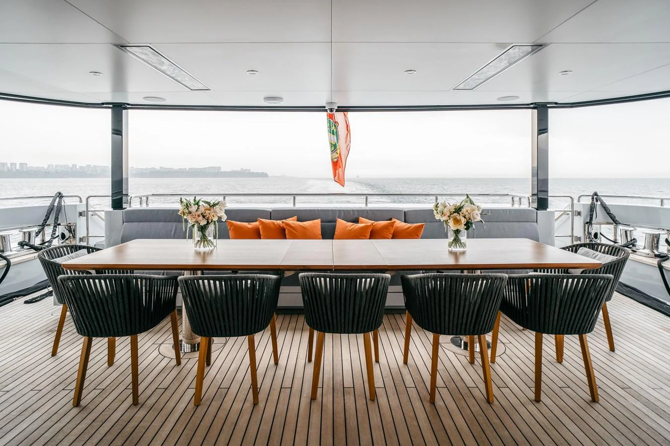 The aft deck features an elegant dining area with a long table and comfortable seating, perfect for alfresco meals with a view of the sea. aboard BERING 145 Yacht for Sale