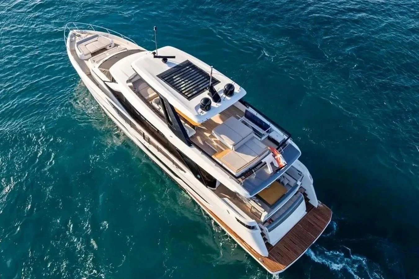 A sleek yacht cruises through clear blue waters, showcasing its spacious flybridge and modern design. aboard SAVIENNE Yacht for Sale