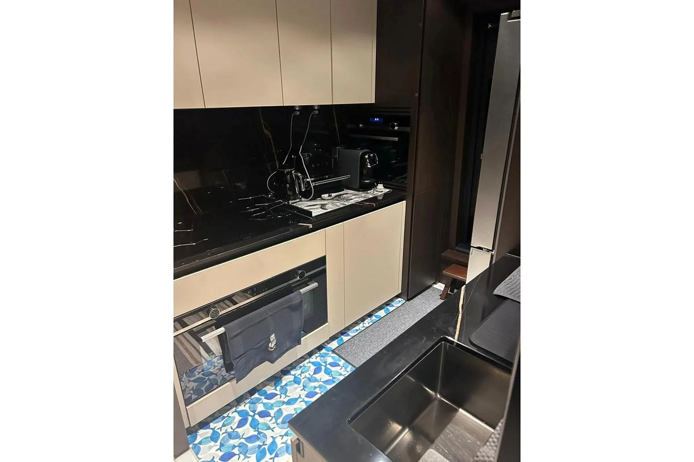 The yacht's galley features modern appliances and a stylish design with a black countertop and patterned flooring. aboard SAVIENNE Yacht for Sale