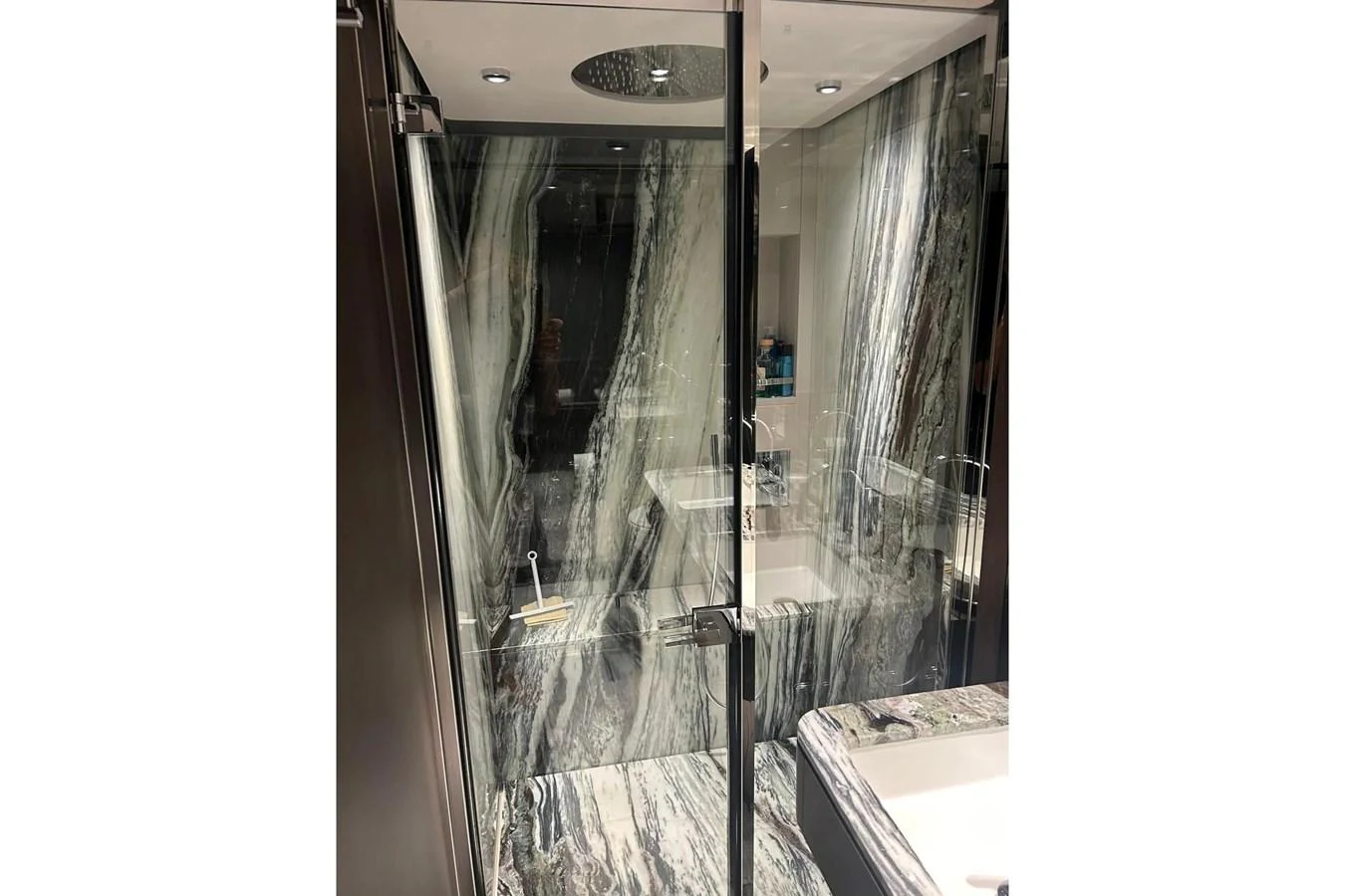 The yacht's bathroom features luxurious marble walls and a modern glass shower enclosure. aboard SAVIENNE Yacht for Sale