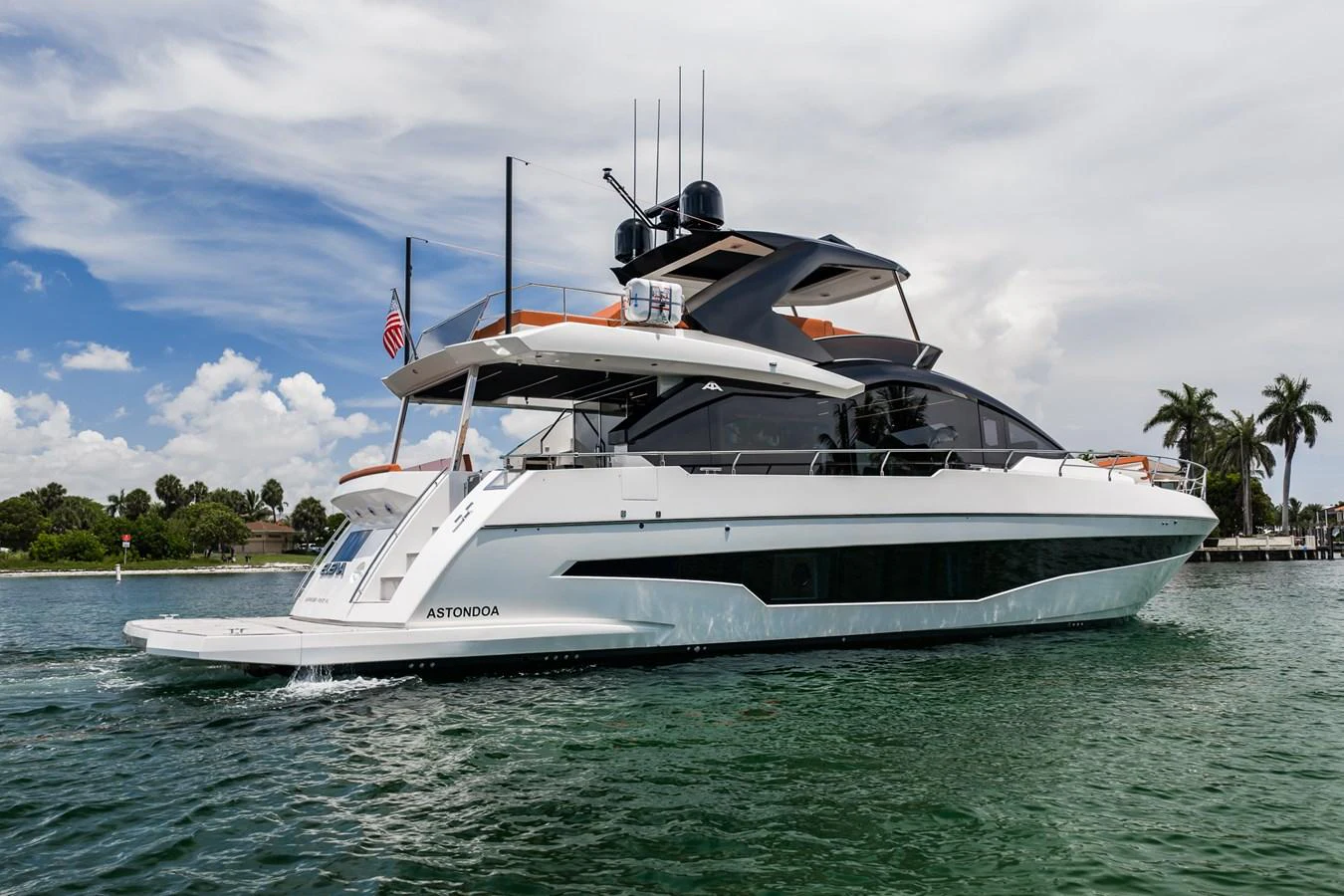 A sleek and modern yacht glides through calm waters under a partly cloudy sky. aboard ELENA Yacht for Sale