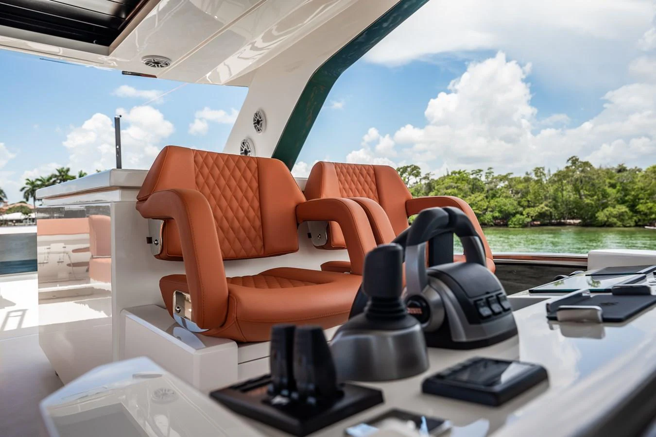 The helm station features luxurious leather seating and state-of-the-art controls, set against a backdrop of serene waters and lush greenery. aboard ELENA Yacht for Sale