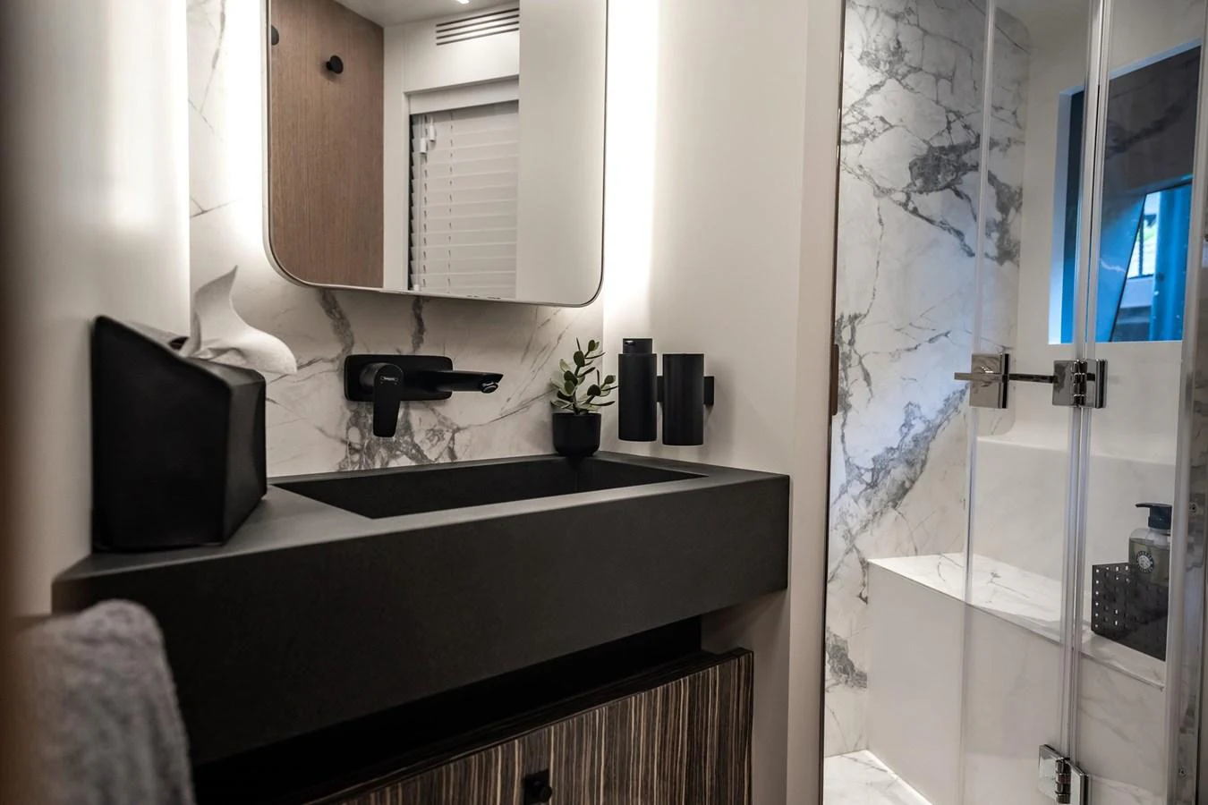 A modern yacht bathroom featuring a sleek black sink and a marble shower. aboard ELENA Yacht for Sale