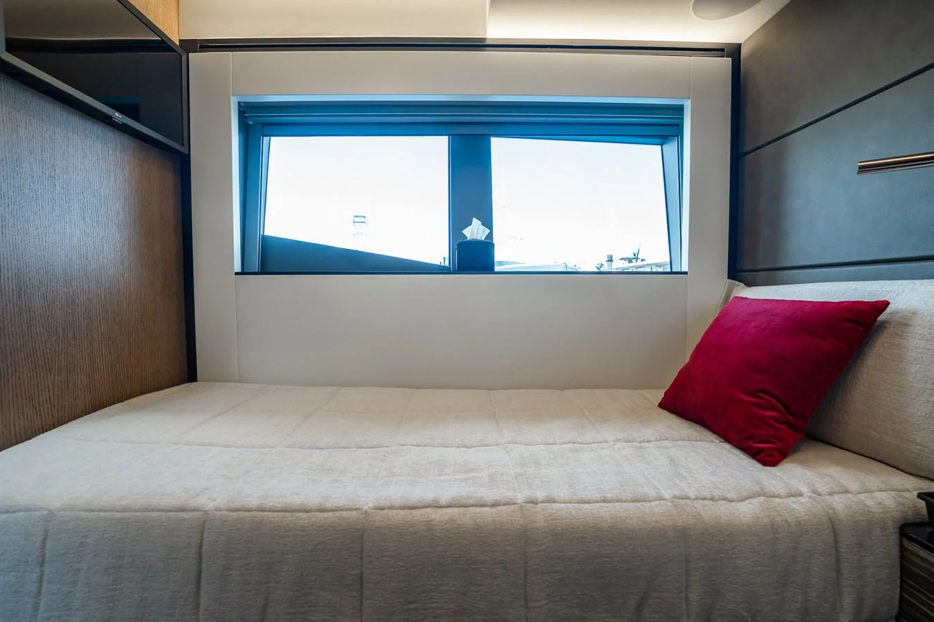 A cozy stateroom with a large window and a plush bed adorned with a red pillow. aboard ELENA Yacht for Sale