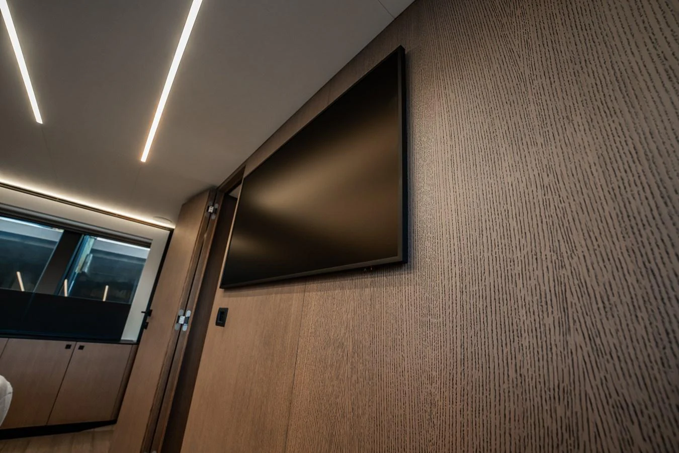 A sleek and modern interior space featuring a large flat-screen TV mounted on a wooden wall. aboard ELENA Yacht for Sale