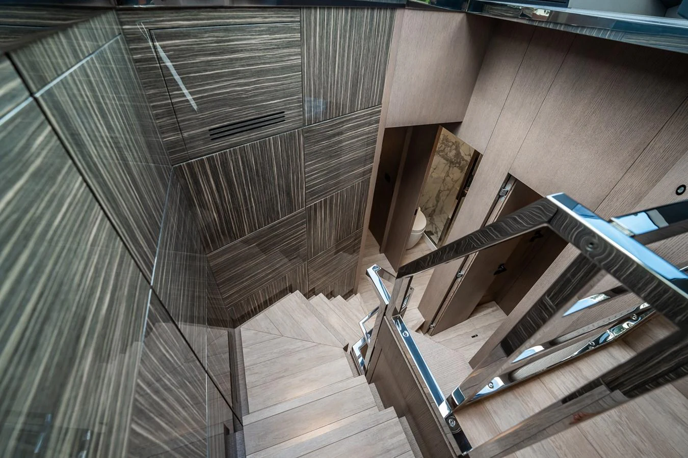 A modern yacht staircase with sleek wood paneling and polished metal railings. aboard ELENA Yacht for Sale