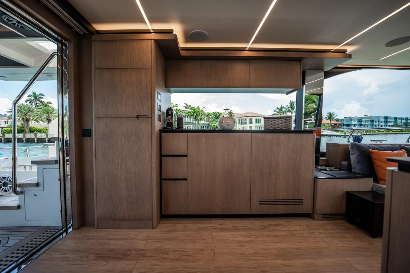 The yacht's galley features sleek wooden cabinetry and modern appliances, with a view of the water through large windows. aboard ELENA Yacht for Sale