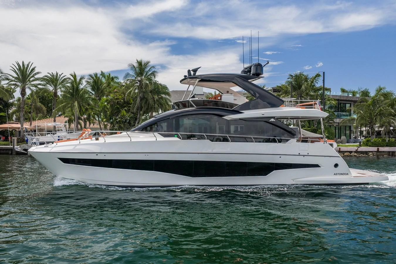 A sleek and modern yacht cruises along a tropical waterfront, showcasing its elegant design and spacious decks. aboard ELENA Yacht for Sale