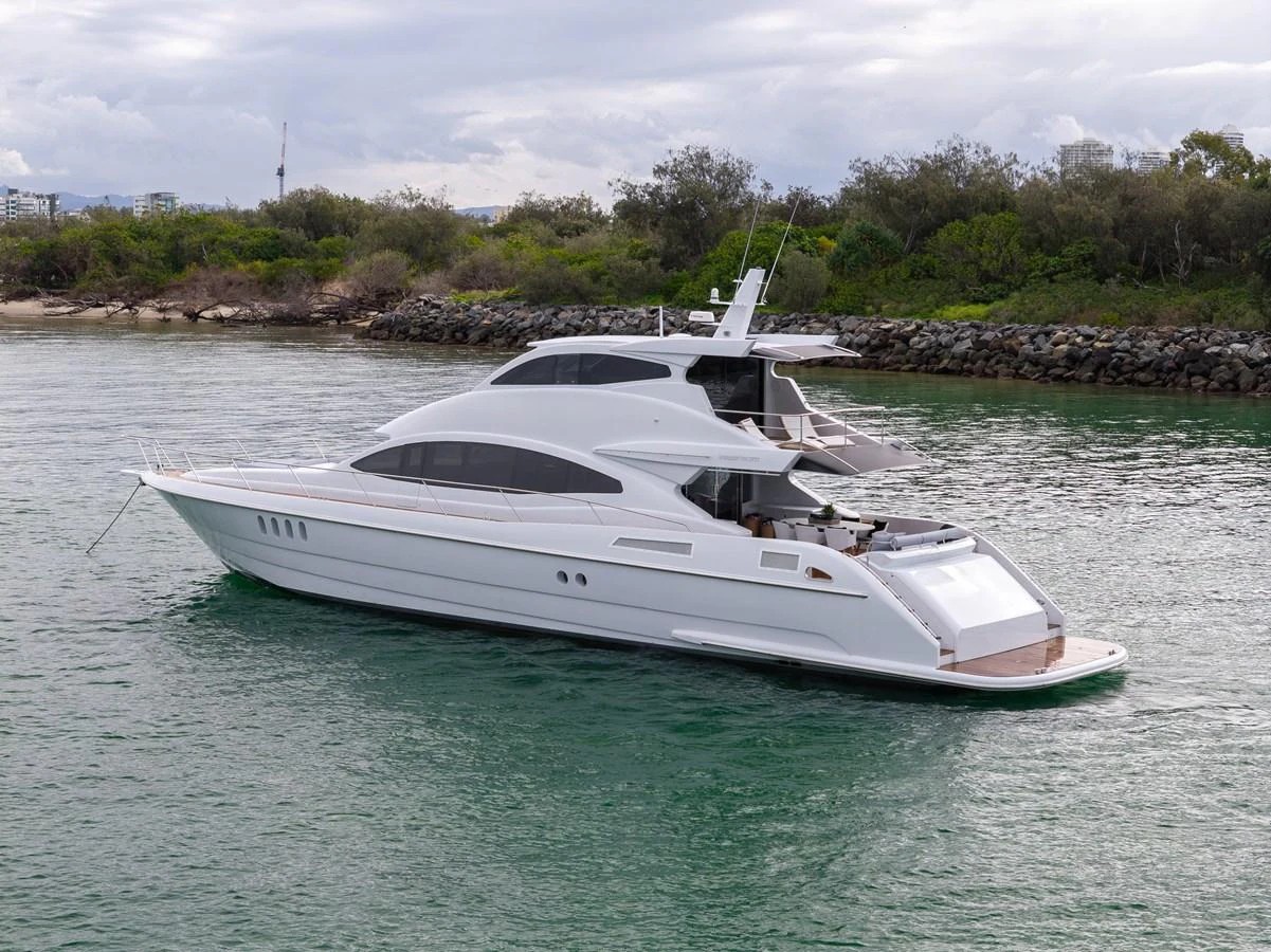 A sleek and modern yacht glides gracefully on calm waters near a lush shoreline. aboard WARREN 87 Yacht for Sale