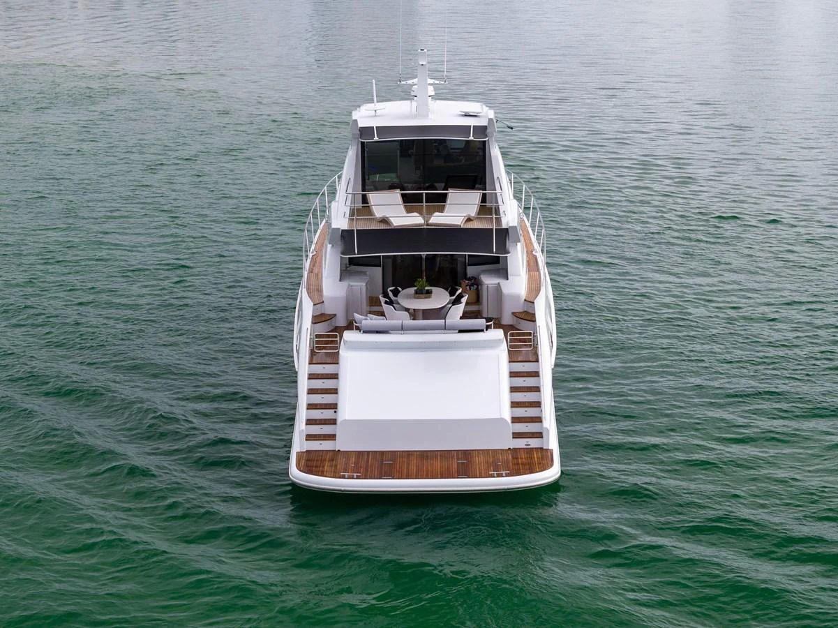 A sleek yacht is seen from the rear, showcasing its spacious decks and elegant design on calm waters. aboard WARREN 87 Yacht for Sale