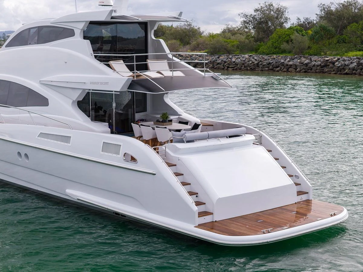 The yacht's sleek aft deck features a spacious lounging area with elegant wooden flooring. aboard WARREN 87 Yacht for Sale