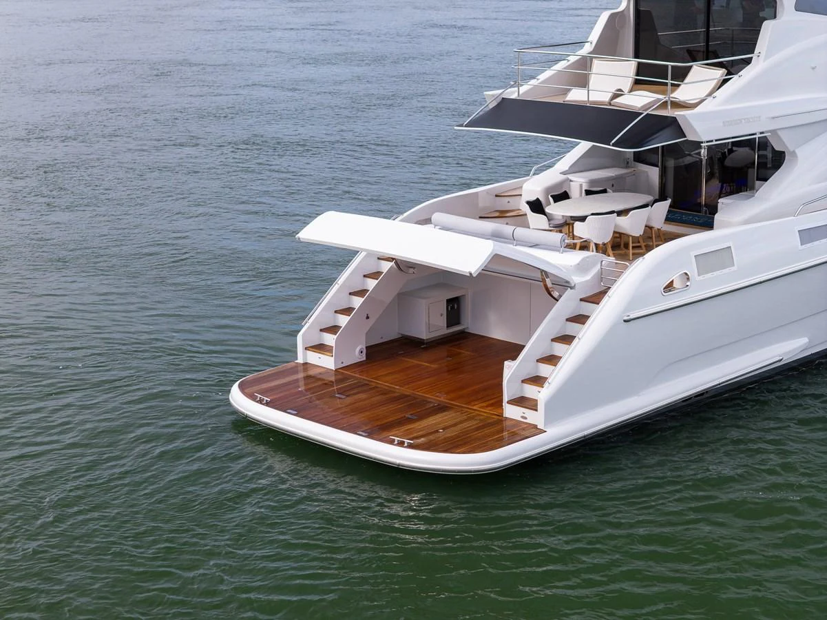 The yacht's aft deck features a spacious swim platform with elegant wooden steps leading up to the main deck. aboard WARREN 87 Yacht for Sale