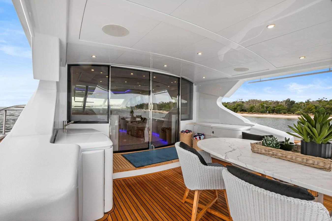 The aft deck features a stylish dining area with a view of the interior through sliding glass doors. aboard WARREN 87 Yacht for Sale