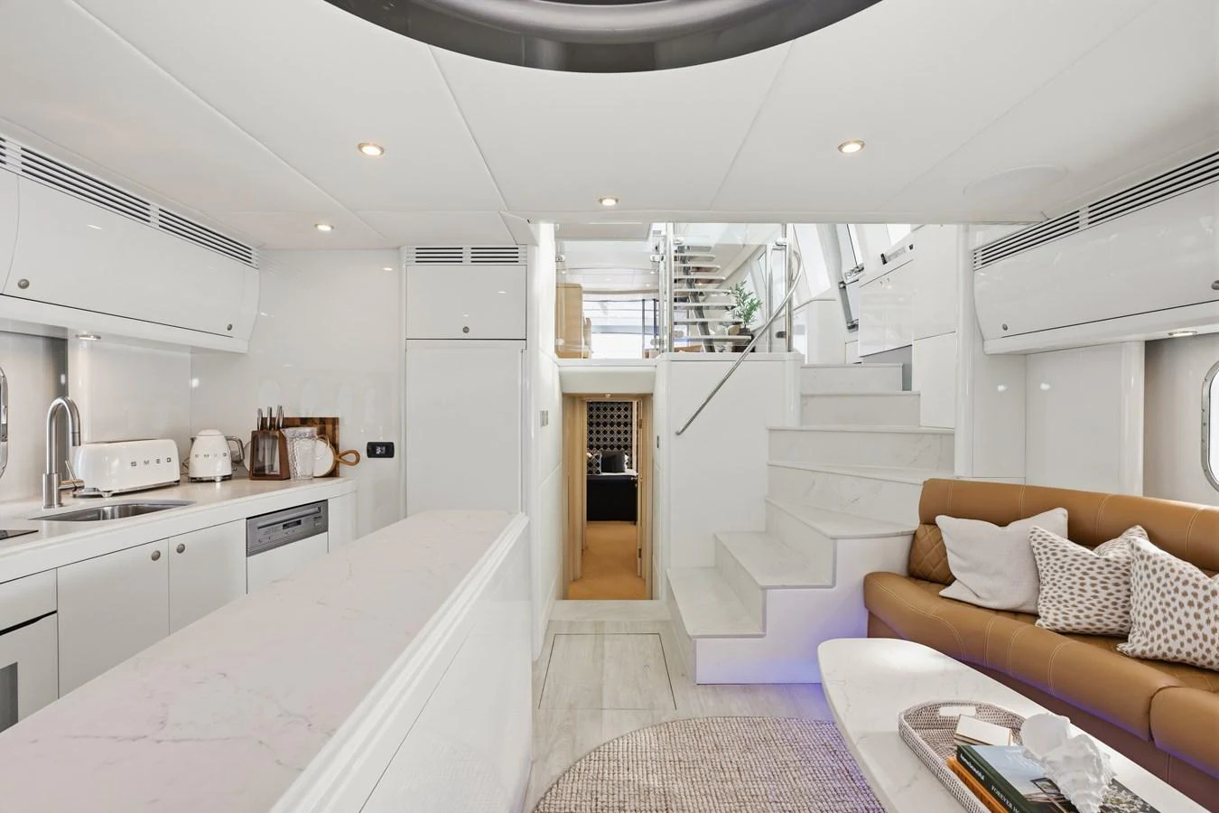 The yacht's galley features modern appliances and a comfortable seating area with a staircase leading to the upper deck. aboard WARREN 87 Yacht for Sale