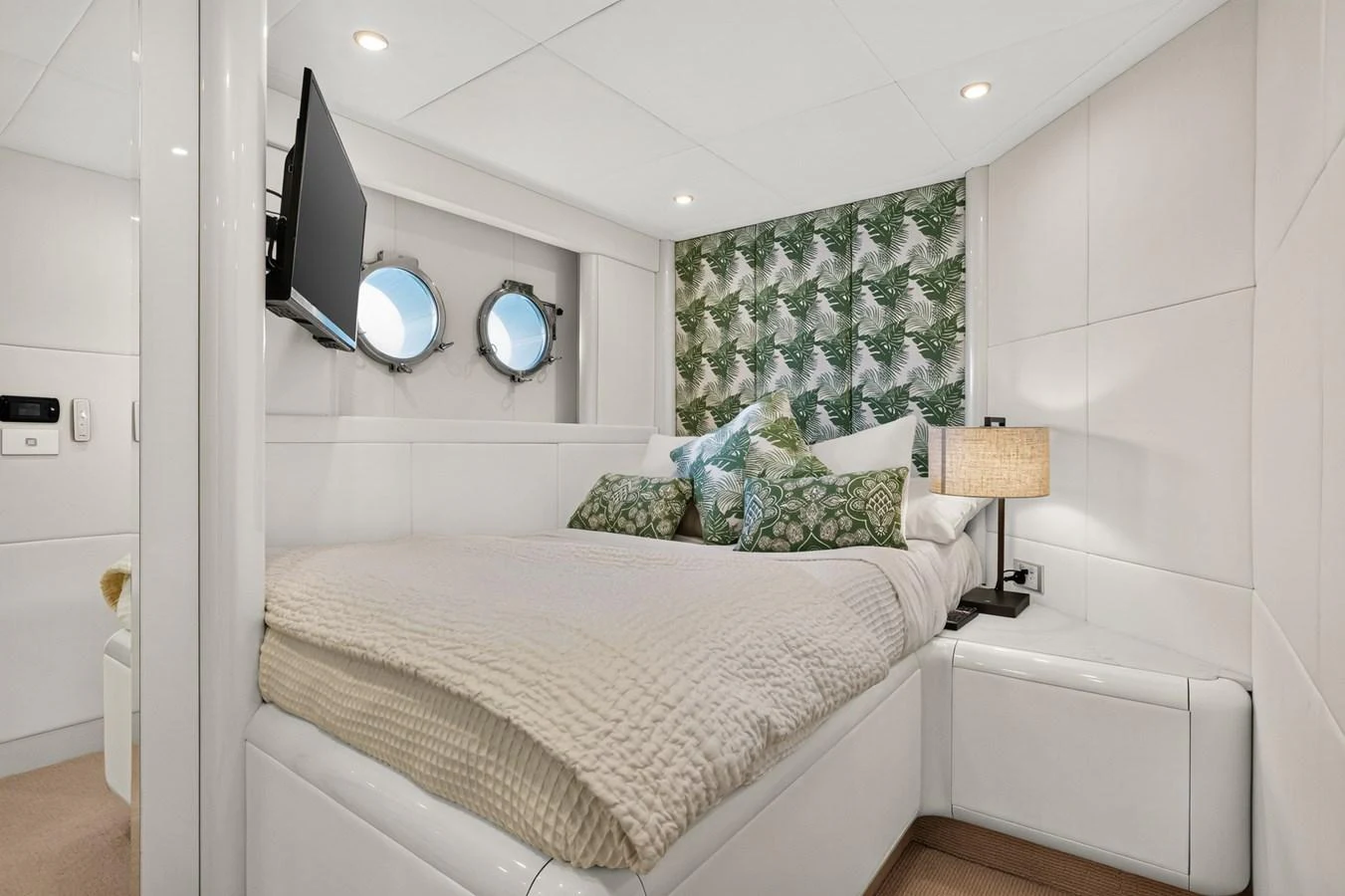 The stateroom features a cozy bed with elegant bedding and a stylish decor accentuated by porthole windows. aboard WARREN 87 Yacht for Sale