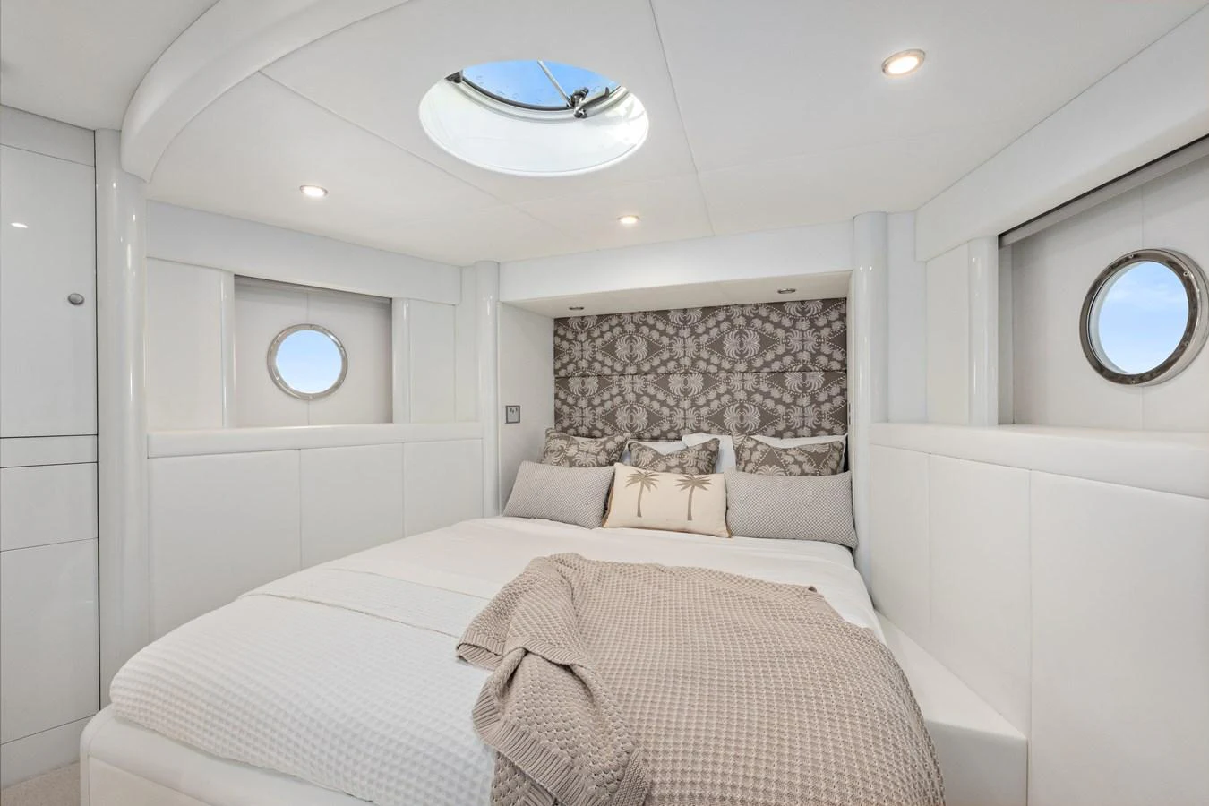 A cozy stateroom with a double bed, porthole windows, and modern decor. aboard WARREN 87 Yacht for Sale