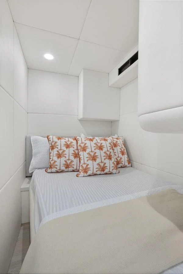 A cozy yacht cabin featuring a comfortable bed with decorative pillows and soft lighting. aboard WARREN 87 Yacht for Sale