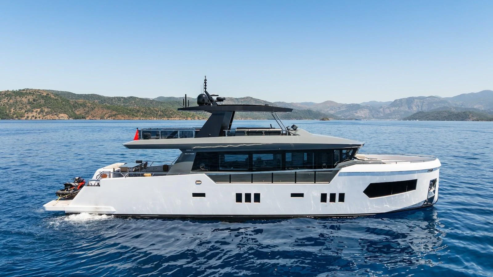 A sleek and modern yacht cruising on calm blue waters with a scenic backdrop. aboard FERRO 77 Yacht for Sale