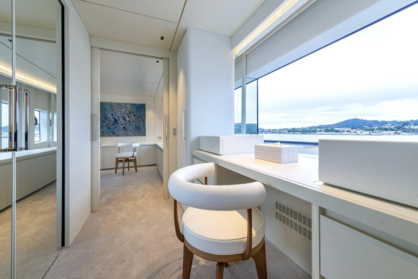 The yacht's interior features a serene and modern workspace with a large window offering a scenic view. aboard AMER 120/11 Yacht for Sale