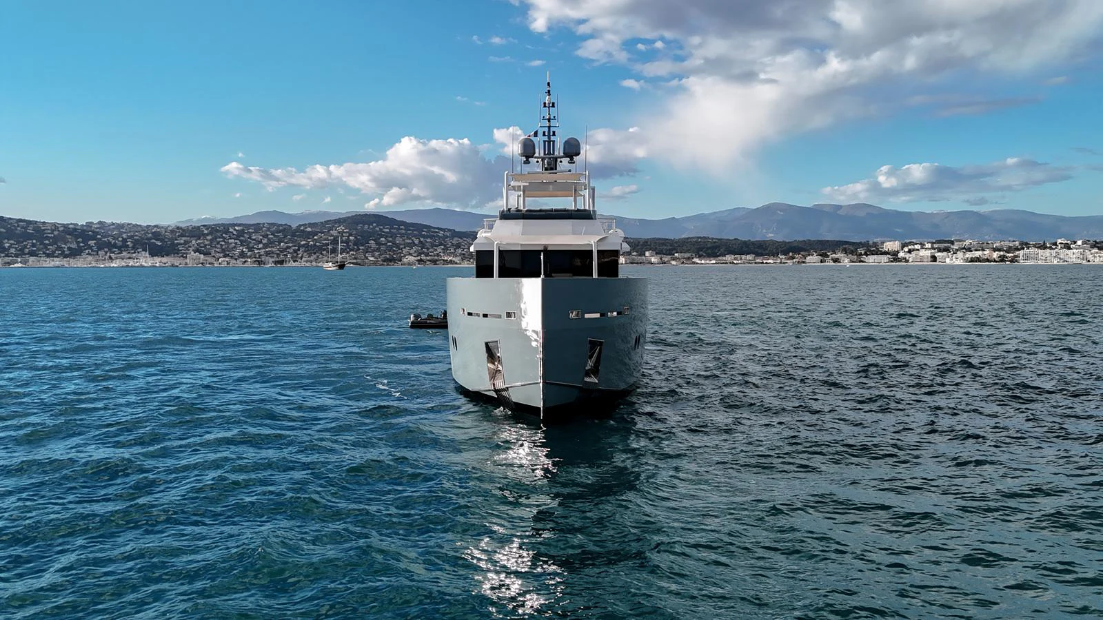 A sleek yacht cruises on calm waters with a scenic coastal backdrop. aboard ONLY NOW Yacht for Sale