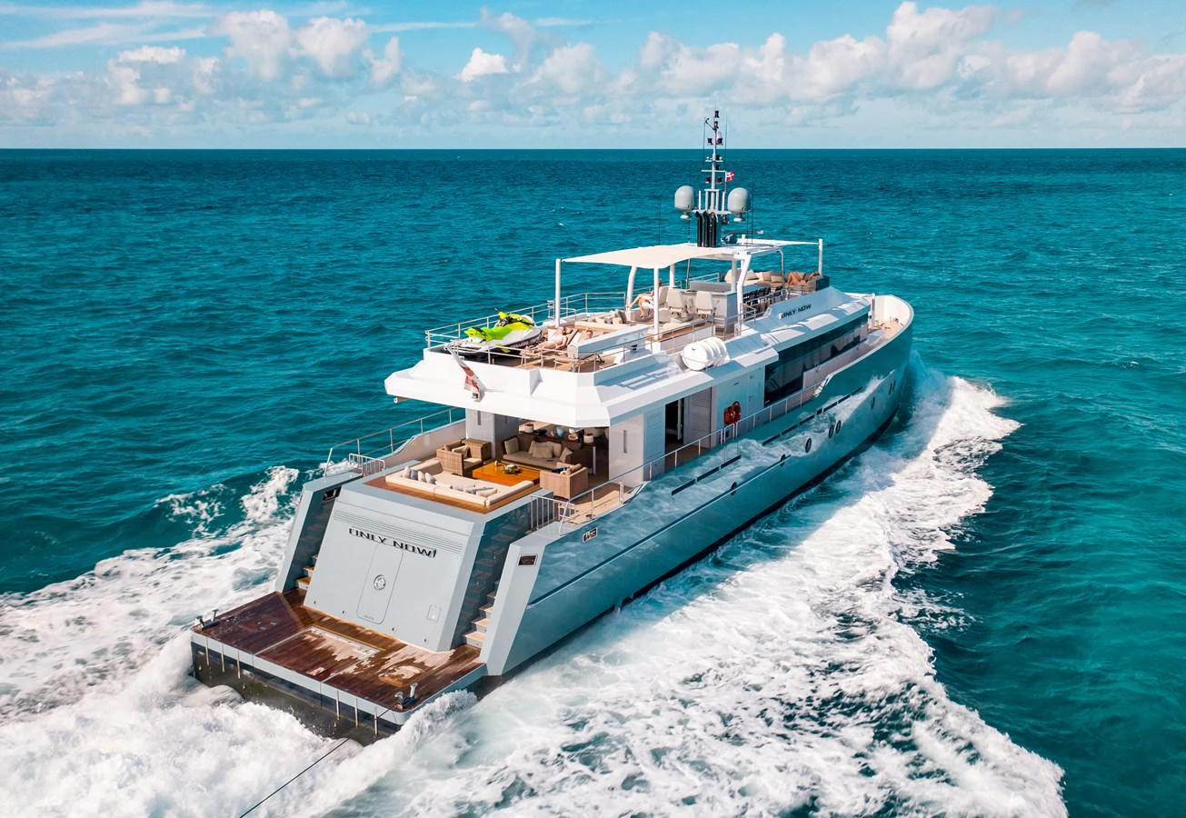 A sleek and modern yacht cruises through the open sea, showcasing its spacious aft deck and luxurious amenities. aboard ONLY NOW Yacht for Sale