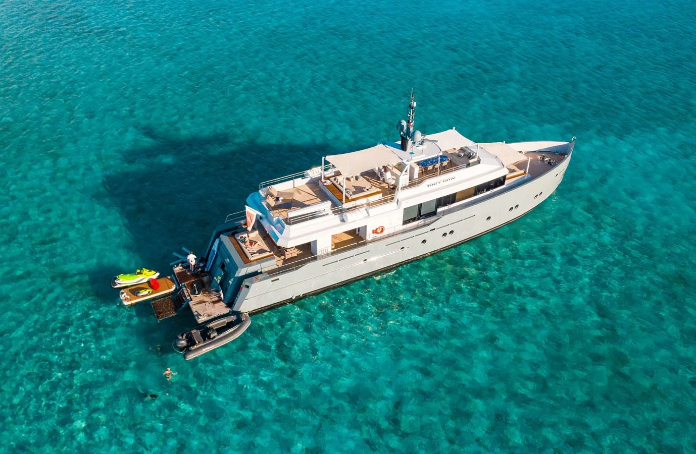 A sleek yacht cruises through crystal-clear waters, showcasing its luxurious design and ample deck space. aboard ONLY NOW Yacht for Sale