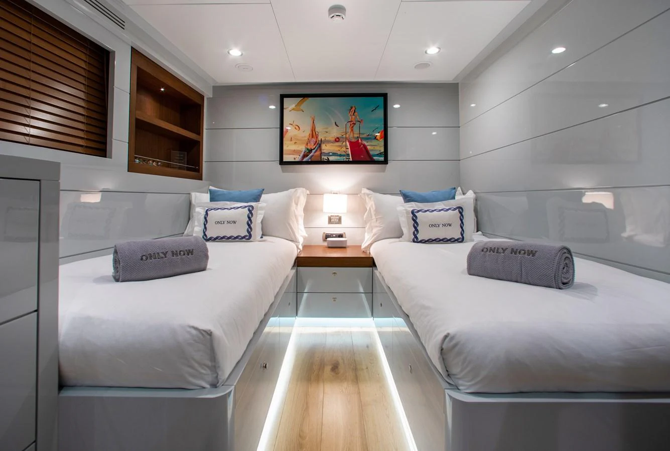 The guest stateroom features twin beds with elegant bedding and ambient lighting. aboard ONLY NOW Yacht for Sale