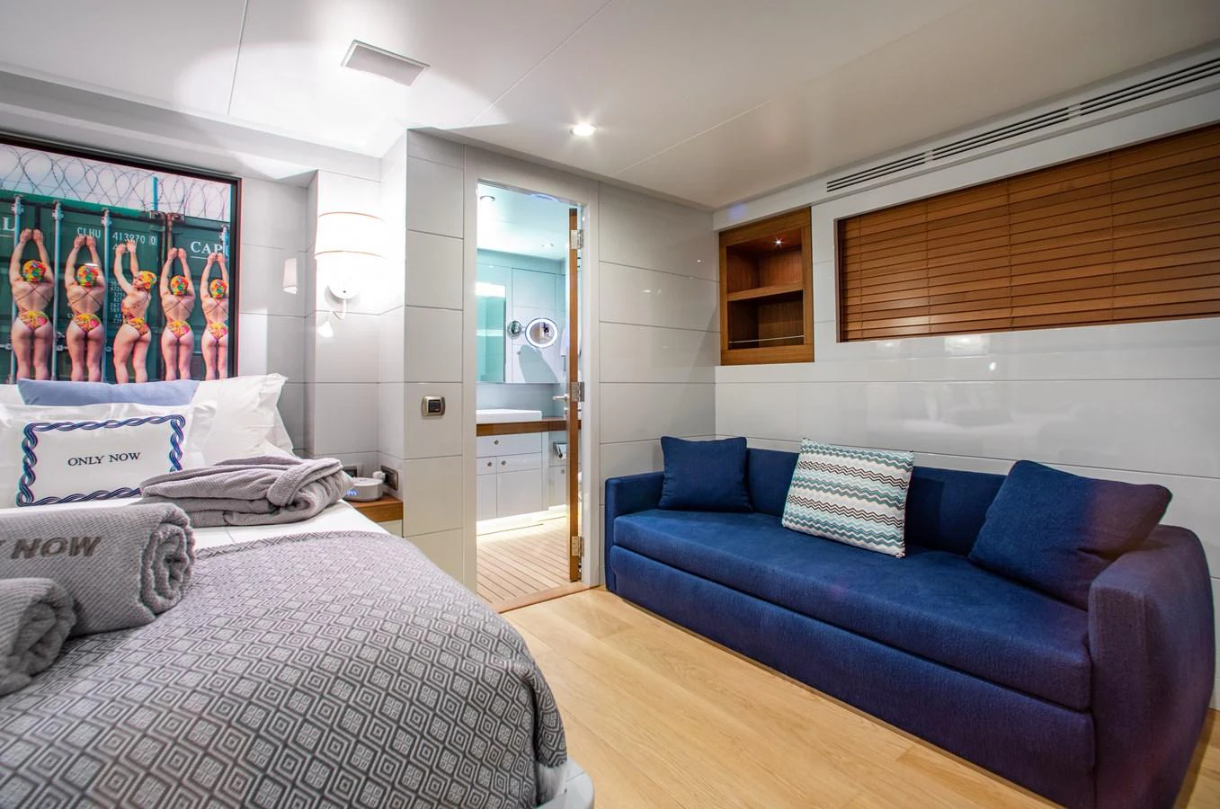 A cozy stateroom featuring a comfortable bed, a blue sofa, and modern decor. aboard ONLY NOW Yacht for Sale
