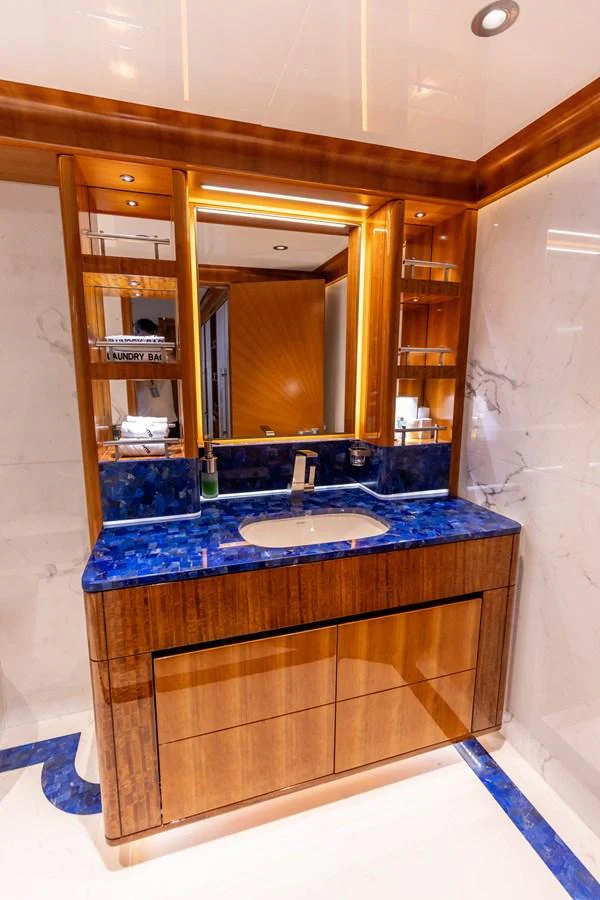 The yacht's bathroom features luxurious finishes with a striking blue countertop and elegant wood cabinetry. aboard ATLANTIS Yacht for Sale