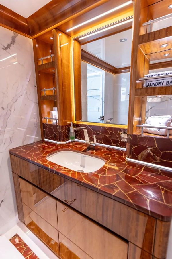 The yacht's bathroom features luxurious marble countertops and elegant wood finishes. aboard ATLANTIS Yacht for Sale